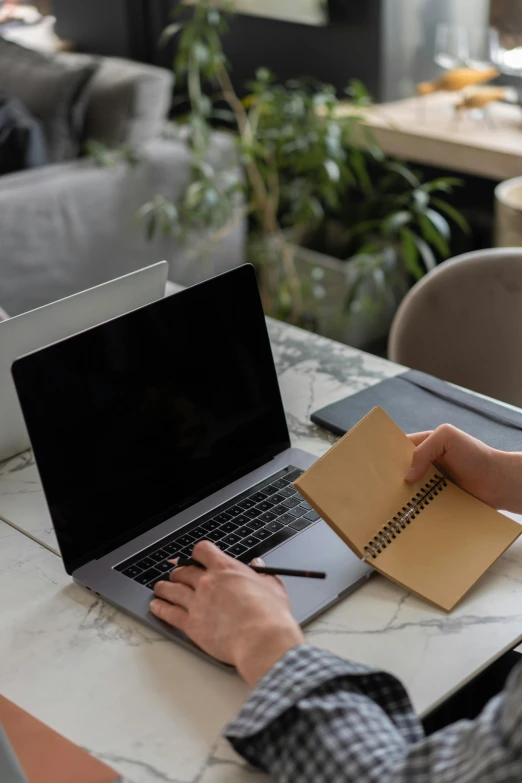 a person sitting at a table working on a laptop, holding notebook, less detailing, brown, monthly