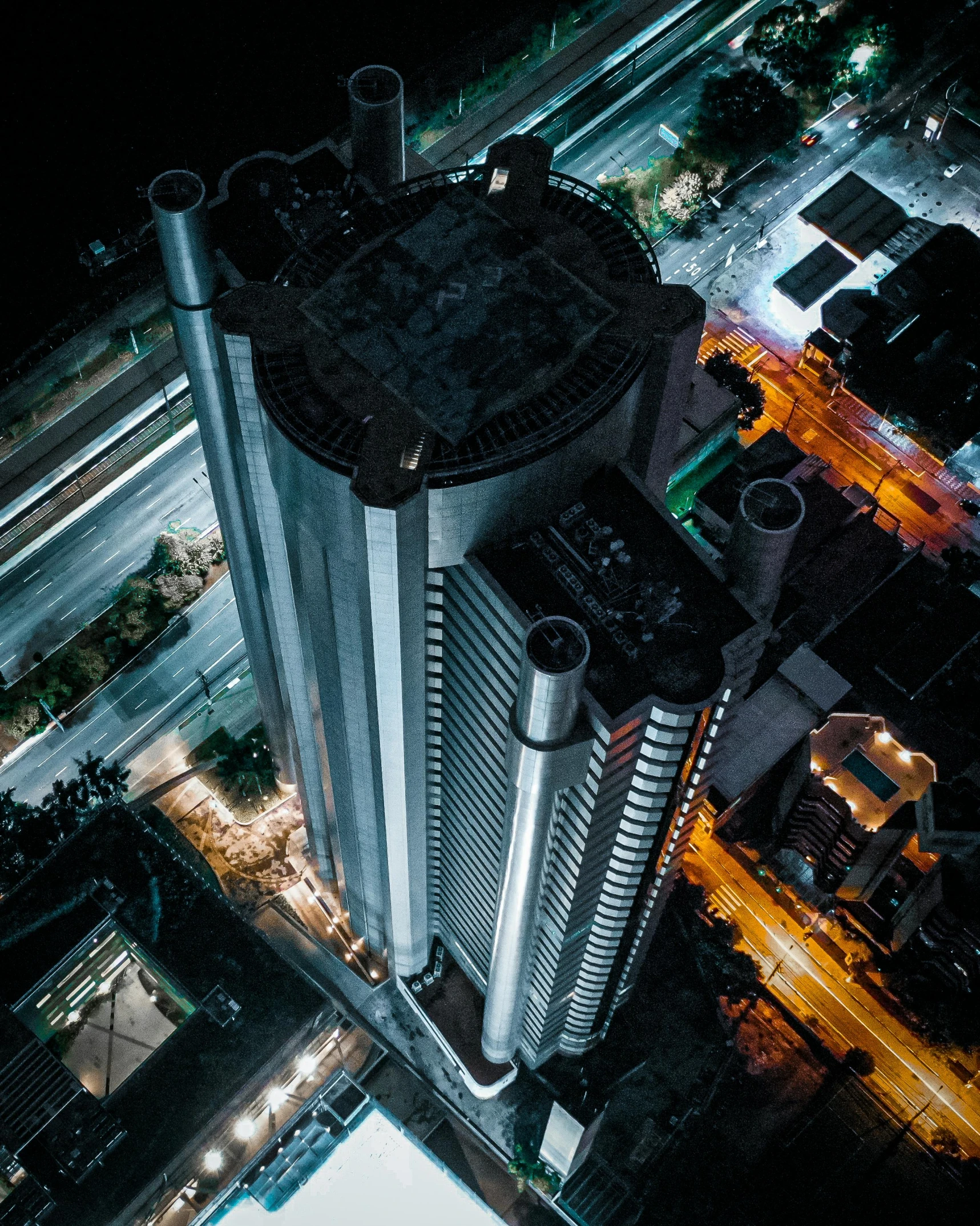 an aerial view of a city at night, unsplash contest winner, brutalism, tall skyscraper, apartment complex made of tubes, thumbnail, upscale photo