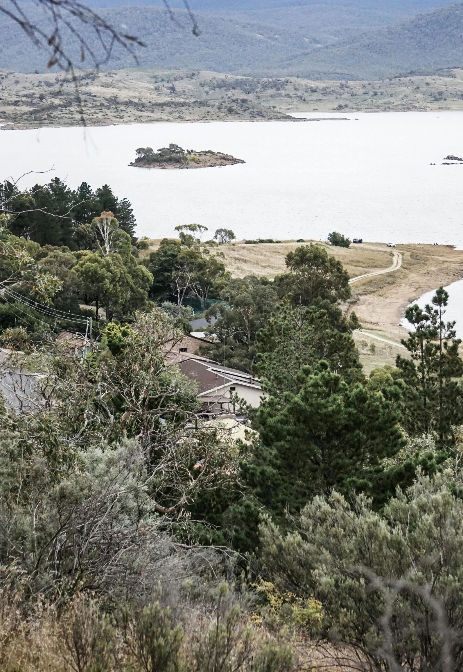 a large body of water surrounded by trees, inspired by Wilhelm Marstrand, hurufiyya, on top of a hill, manuka, overview, rocky ground with a dirt path