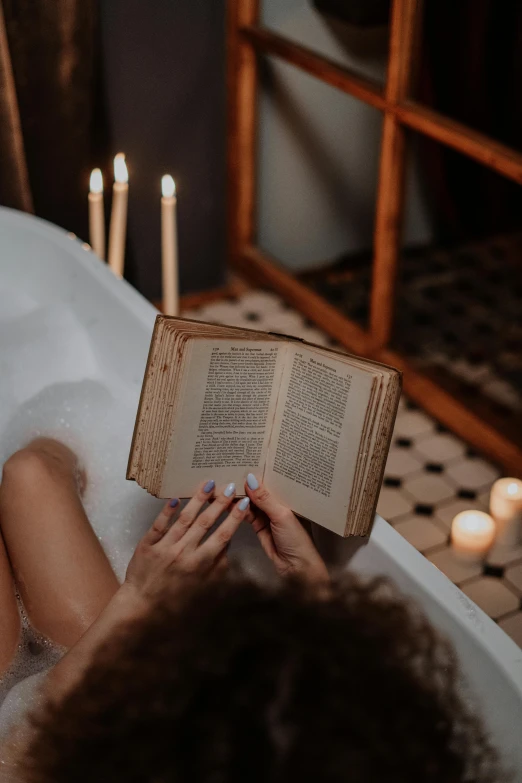 a woman sitting in a bathtub reading a book, pexels contest winner, romanticism, waxy candles, 💣 💥💣 💥, reading for a party, doing witchcraft