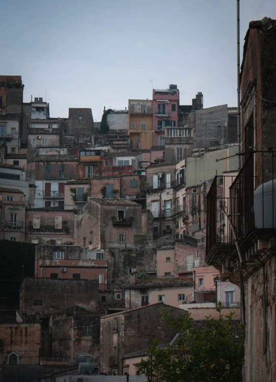 a very tall building sitting in the middle of a city, an album cover, by Davide Sasselli, pexels contest winner, terraced, sicilian, grey, early evening