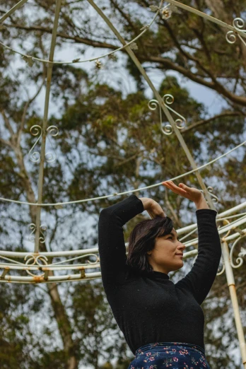 a woman standing on top of a metal structure, by Winona Nelson, unsplash, arabesque, sydney park, the empress’ swirling gardens, with arms up, profile image