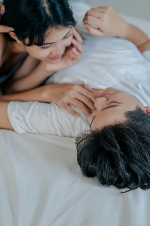 a man laying on top of a bed next to a woman, trending on unsplash, lesbian embrace, asian women, whispers, high angle close up shot