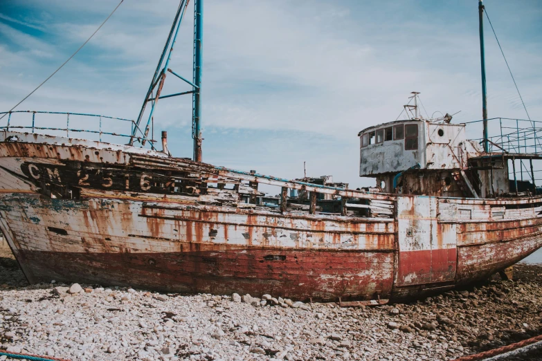a rusty boat sitting on top of a rocky beach, pexels contest winner, shipyard, full body image, thumbnail, full faced