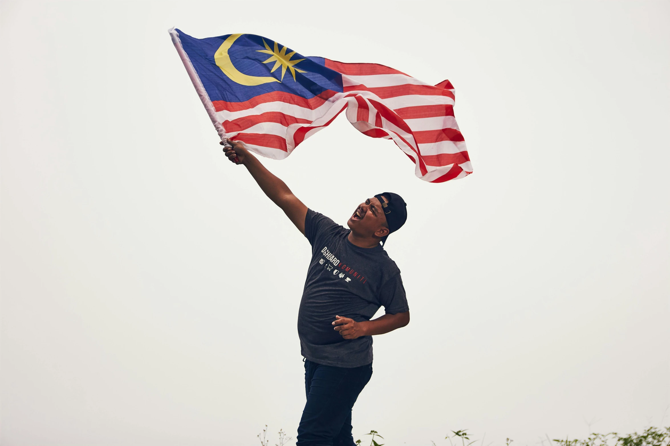 a man holding a malaysian flag on top of a hill, by Matthias Stom, hurufiyya, outlive streetwear collection, portrait of figther jet evading, sza, shot on sony a 7