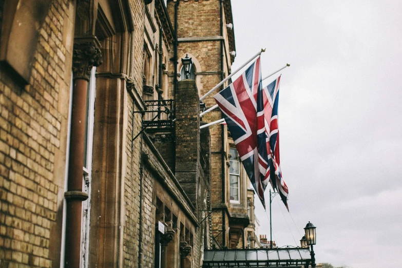 a couple of flags hanging from the side of a building, unsplash, victorian buildings, hotel, english countryside, profile image