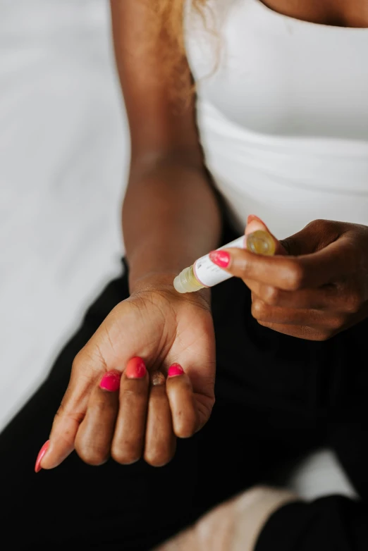 a woman sitting on a bed holding a toothbrush, by Arabella Rankin, trending on pexels, process art, offering the viewer a pill, inking on skin, mamou - mani, left eye red stripe