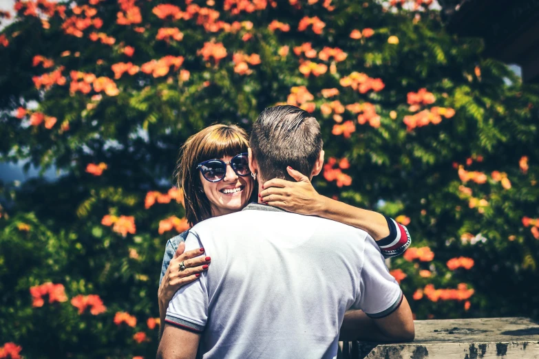 a man and woman hugging each other in front of a tree, pexels contest winner, happening, wearing orange sunglasses, in the garden, 15081959 21121991 01012000 4k, digitally enhanced