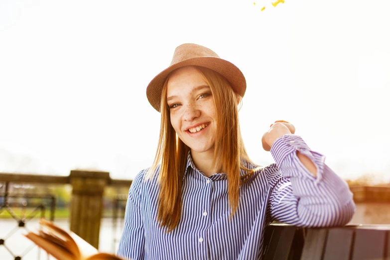 a woman sitting on a bench reading a book, by Julia Pishtar, shutterstock, wearing a chocker and cute hat, wearing stripe shirt, smiling at camera, cute young redhead girl