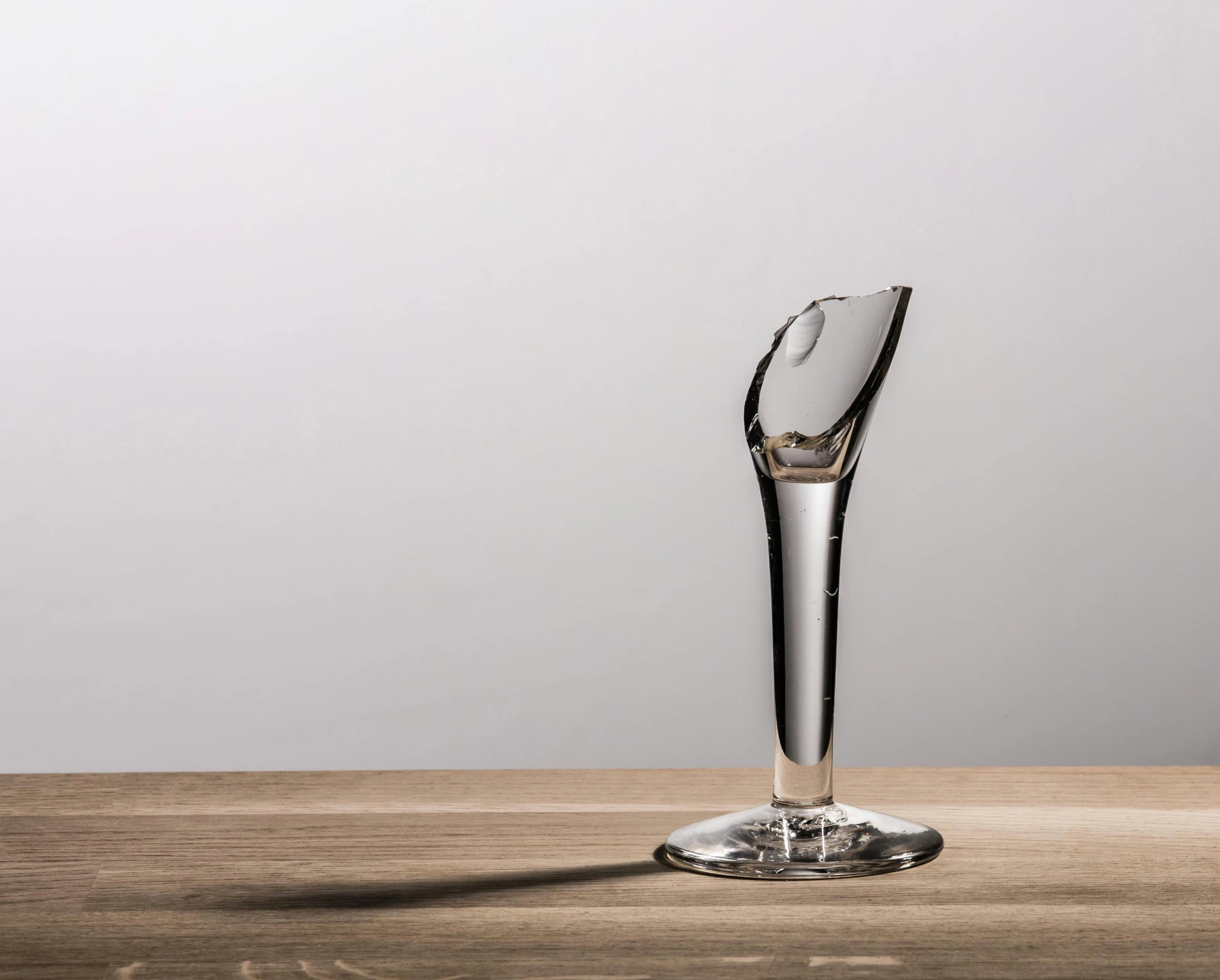 a wine glass sitting on top of a wooden table, an abstract sculpture, inspired by Méret Oppenheim, unsplash, photorealism, portal. zaha hadid, highly detailed product photo, spoon slim figure, transparent