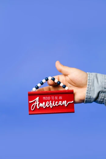 a person holding a red box with beads on it, inspired by Americo Makk, the american dream, billboard image, instagram post, patriotic