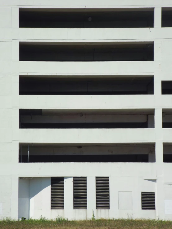 a fire hydrant in front of a parking garage, inspired by Andreas Gursky, brutalism, ignant, white panels, 1990s photograph, balconies
