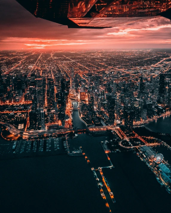 an airplane flying over a city at night, by Adam Marczyński, pexels contest winner, chicago skyline, sunset photo, sitting down, bird\'s eye view