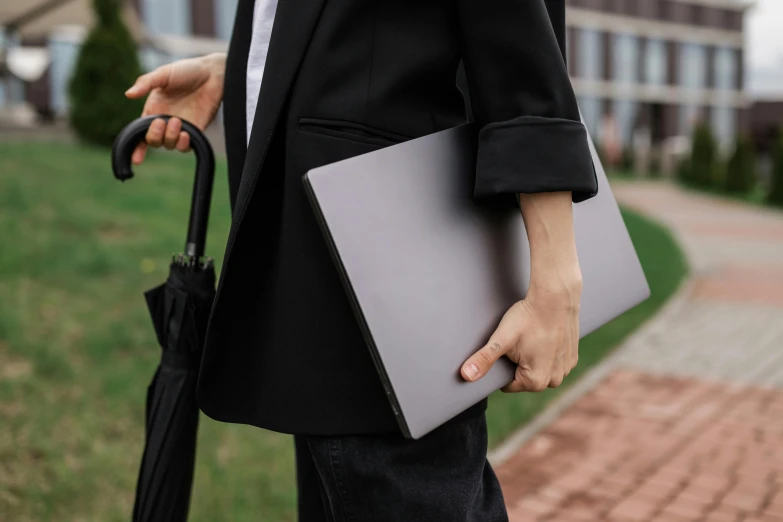 a person holding a laptop and an umbrella, wearing black grey suit, silicone skin, grey, thumbnail