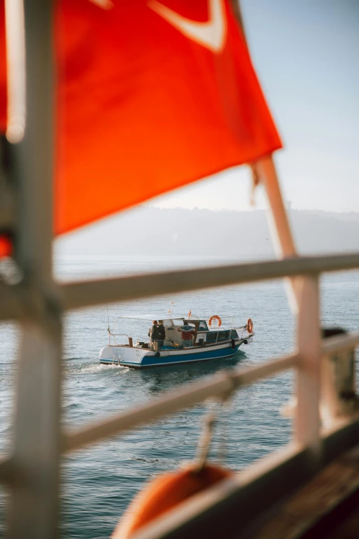 a boat that is out in the water, pexels contest winner, orange and white color scheme, afternoon light, red flags holiday, over-shoulder shot