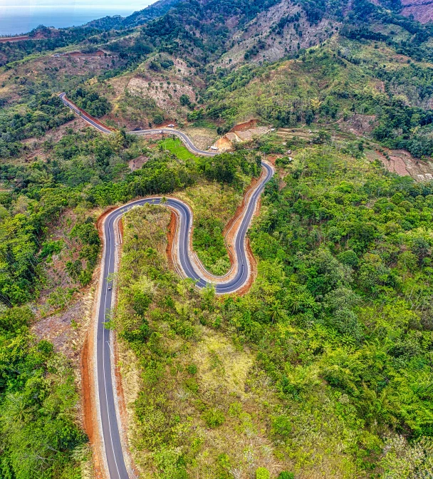 an aerial view of a winding road in the mountains, sumatraism, avatar image