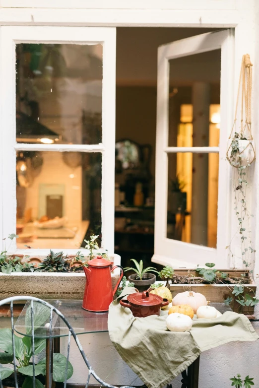 a table and chairs in front of a window, inspired by Henriette Grindat, pexels contest winner, kitchen counter, gardening, in the evening, during autumn