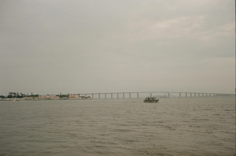 a large body of water with a bridge in the background, inspired by Zhang Kechun, flickr, overcast gray skies, brazil, the photo shows a large, boat