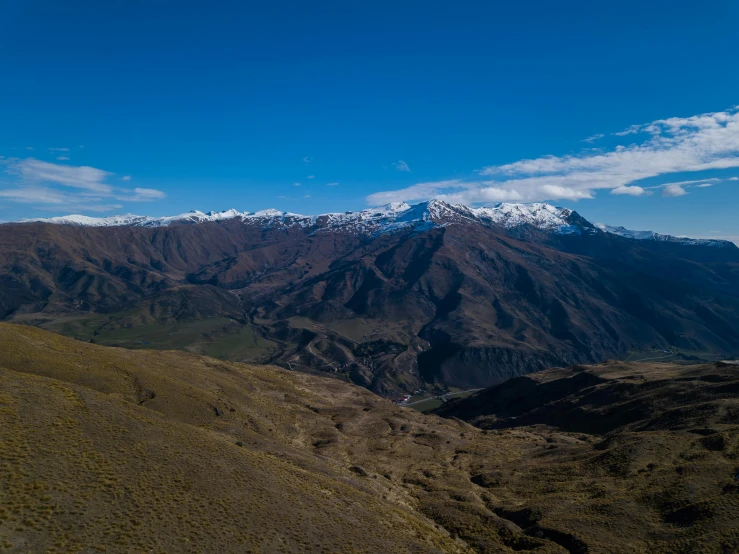 a view of the mountains from the top of a mountain, by Peter Churcher, pexels contest winner, hurufiyya, quechua, clear blue skies, aerial footage, in a valley