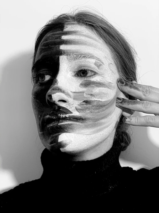 a black and white photo of a woman with white paint on her face, a black and white photo, inspired by Anna Füssli, stripe over eye, with differing emotions, facemask, hand instead of a face