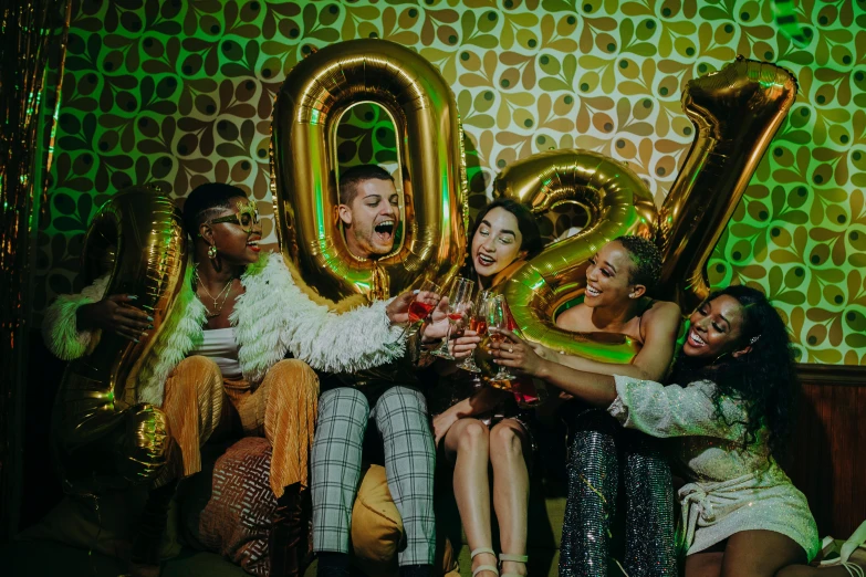 a group of people sitting on top of a couch, trending on pexels, happening, wearing elaborate green and gold, party balloons, dua lipa, photo booth