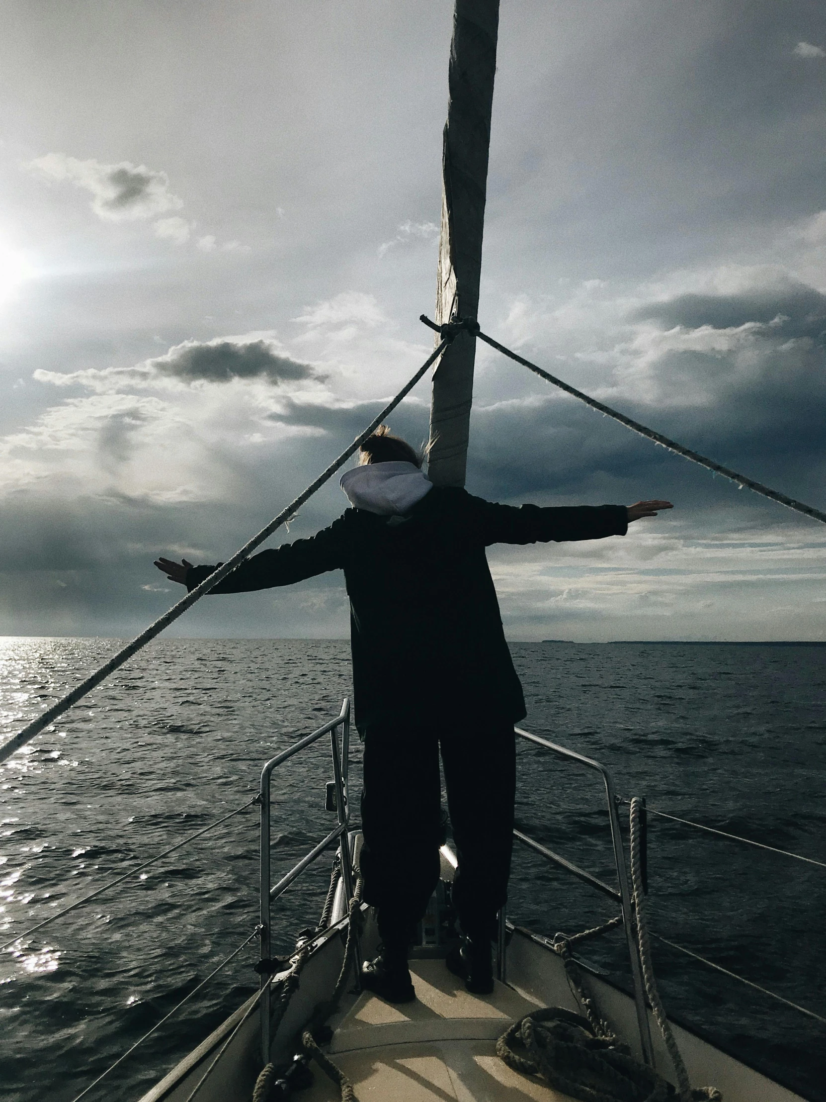 a man standing on top of a boat on a body of water, while it's raining, profile image, sailing boat, triumphant pose