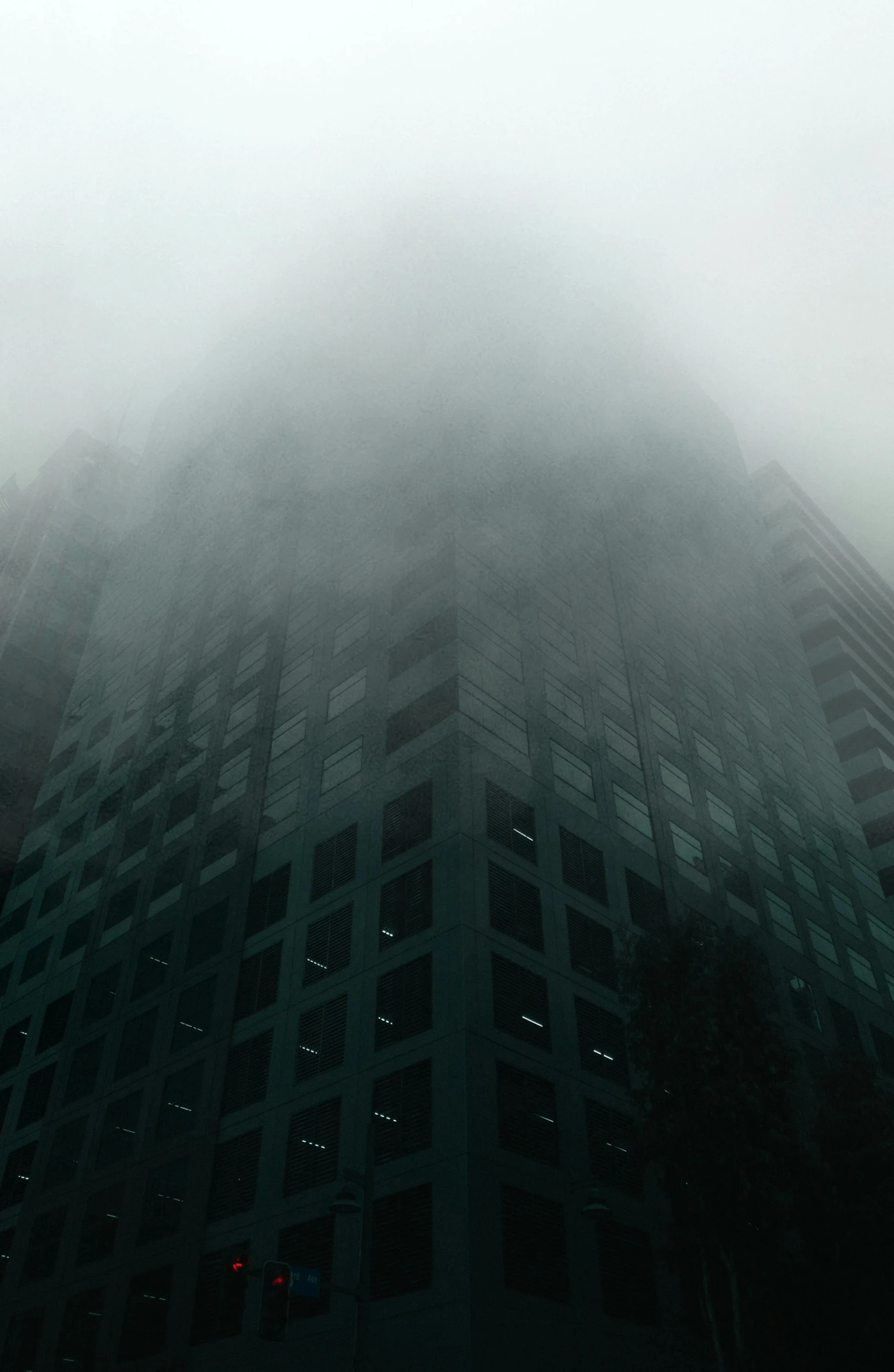 a tall building in the middle of a foggy city, inspired by Elsa Bleda, pexels contest winner, brutalism, ) ominous vibes, green smoggy sky, (((mist))), mysterious exterior