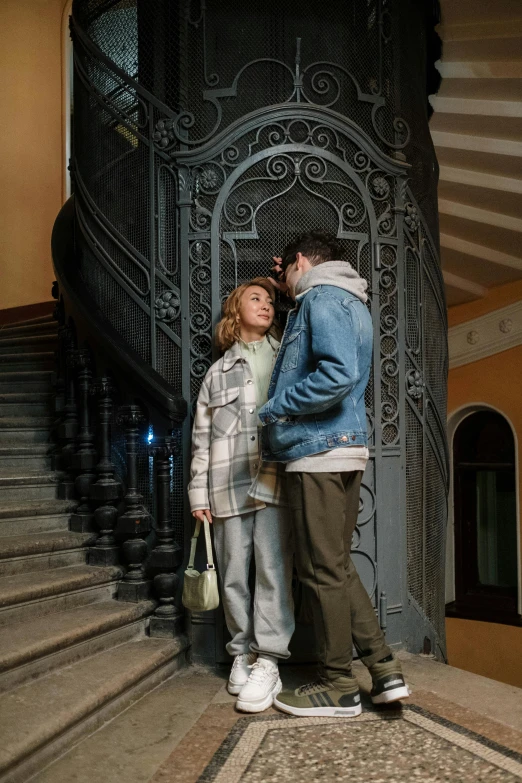 a man and a woman standing in front of a staircase, by Grytė Pintukaitė, pexels contest winner, art nouveau, denim, a cozy, ( ( theatrical ) ), an archway