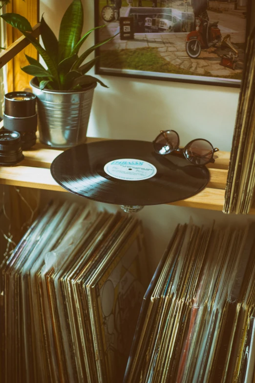 a record sitting on top of a wooden shelf next to a window, by Bernie D’Andrea, trending on pexels, maximalism, shades, having a good time, stacked, curated collection