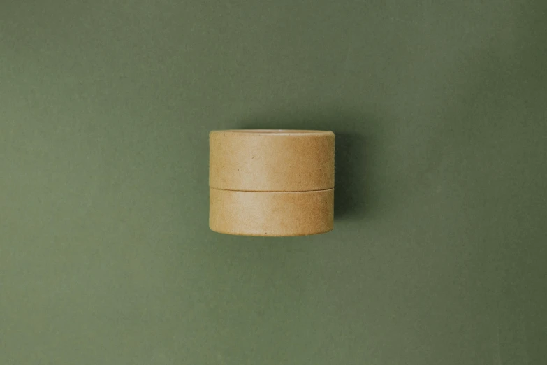 a roll of toilet paper sitting on top of a green wall, by Emma Andijewska, top lid, caramel, on grey background, hemp