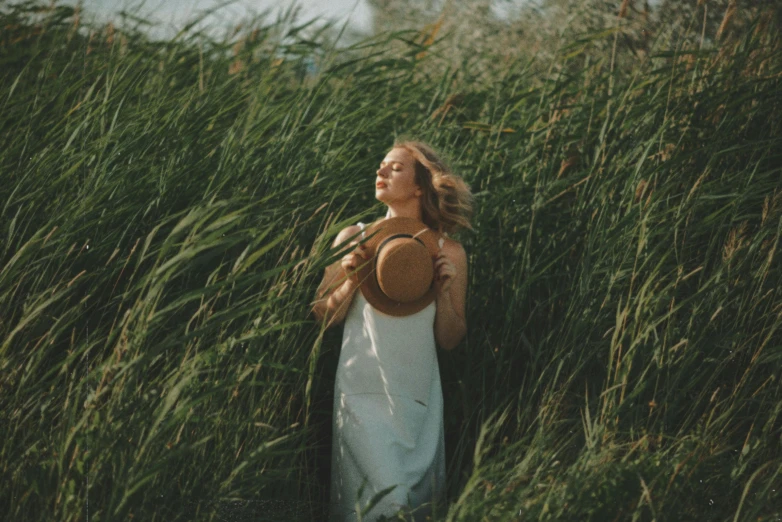 a woman standing in a field of tall grass, by Emma Andijewska, pexels contest winner, renaissance, straw hat, nico wearing a white dress, hair floating in the wind, unsplash photo contest winner