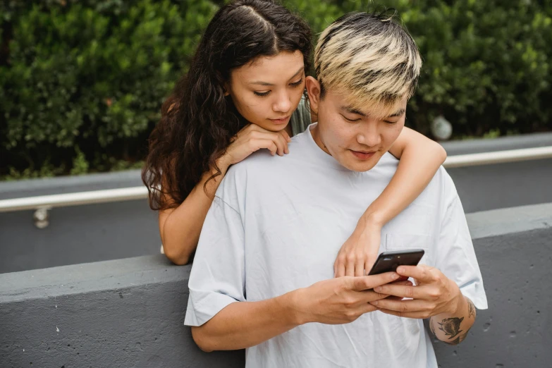 a boy and a girl looking at a cell phone, trending on pexels, of taiwanese girl with tattoos, two men hugging, thumbnail, asian male