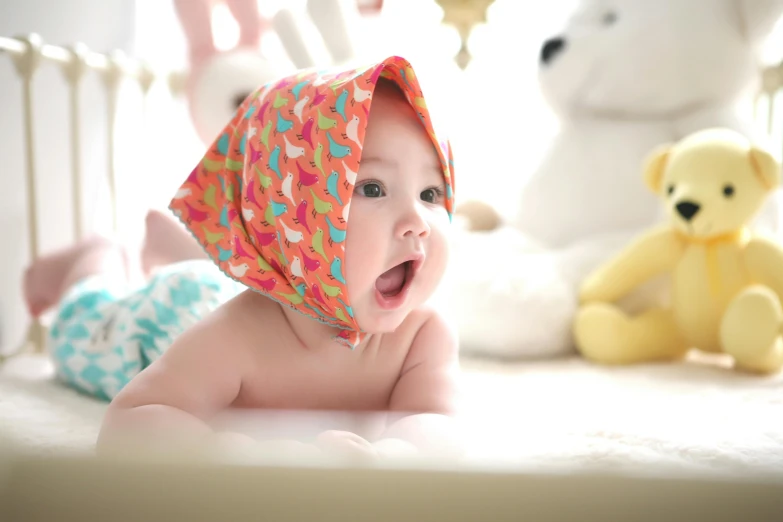 a baby laying in a crib next to stuffed animals, pexels contest winner, pop art, wearing a head scarf, closeup. mouth open, square, diaper-shaped