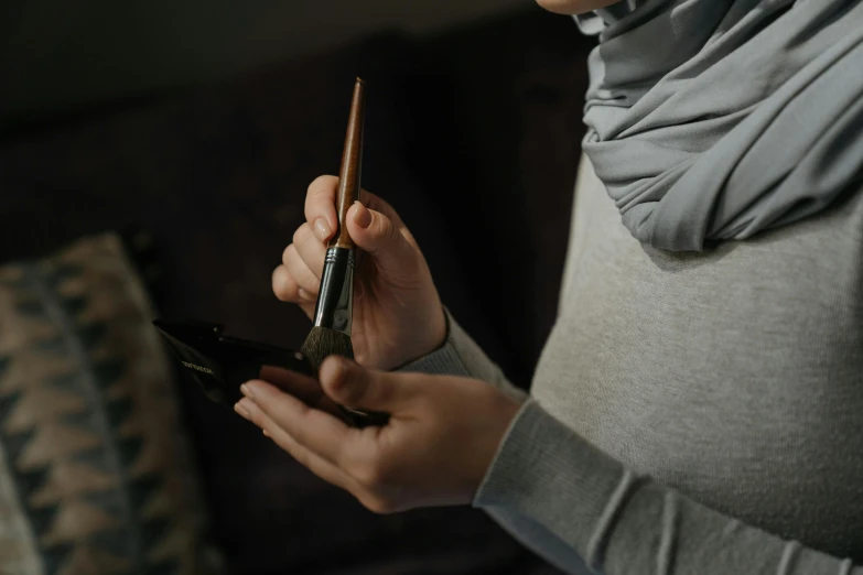 a close up of a person holding a cell phone, a photorealistic painting, inspired by Kyffin Williams, trending on pexels, arbeitsrat für kunst, unsheathing her katana, arabic calligraphy, checking her phone, brown