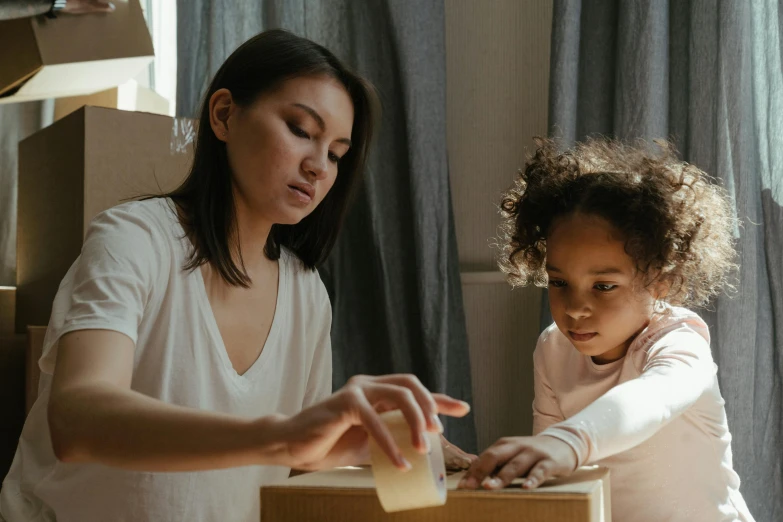 a woman and a little girl playing with a box, pexels contest winner, manuka, avatar image, nursing, concentration