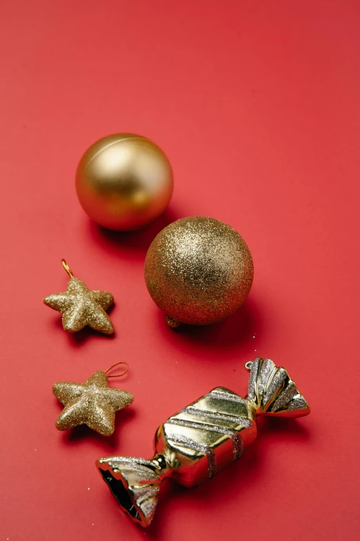 a group of christmas decorations on a red surface, a still life, pexels, grey and gold color palette, petite, product shot, hanging