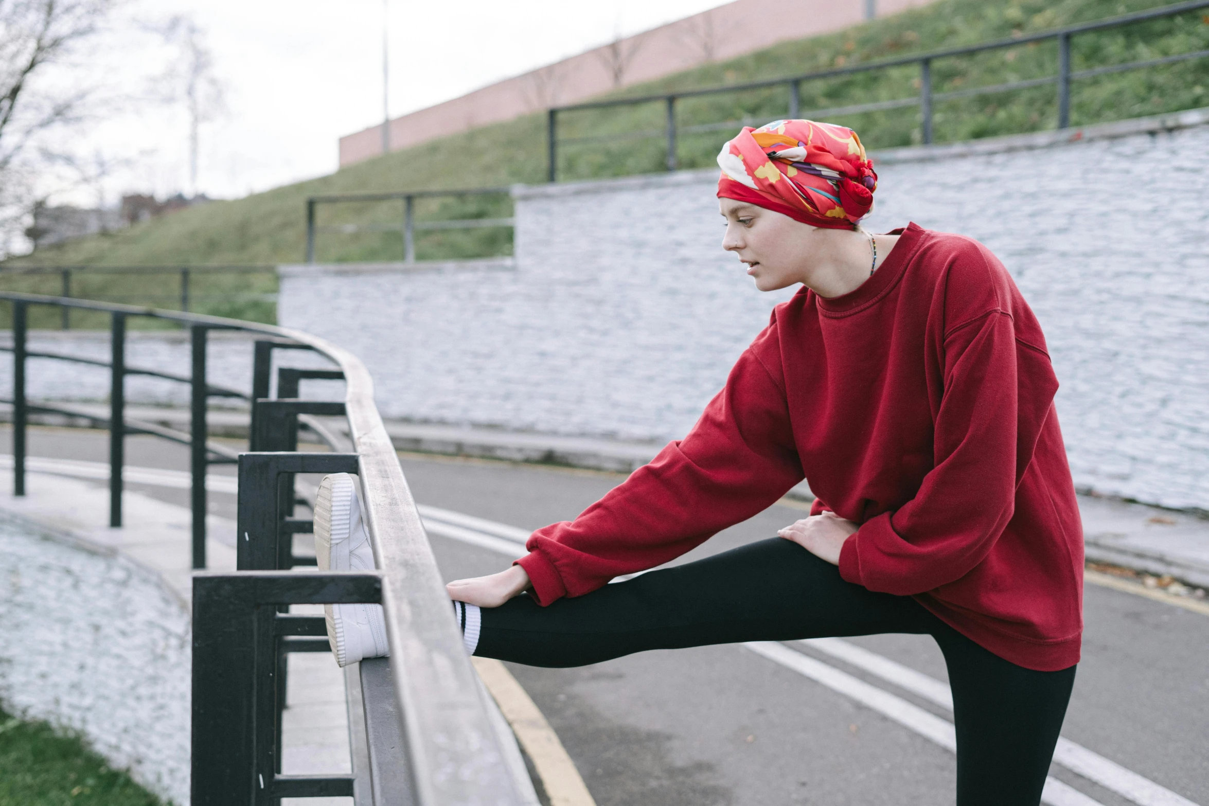 a person on a skateboard leaning on a rail, inspired by Louisa Matthíasdóttir, trending on pexels, happening, cloth head wrap, red sport clothing, 5 k, sitting on bench