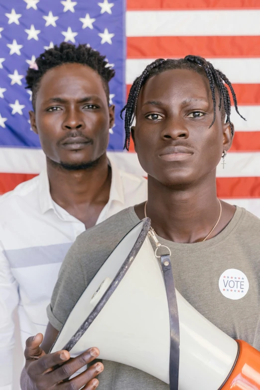 two men holding a megaphone in front of an american flag, by Ellen Gallagher, trending on unsplash, renaissance, adut akech, androgynous face, a pair of ribbed, portrait n - 9