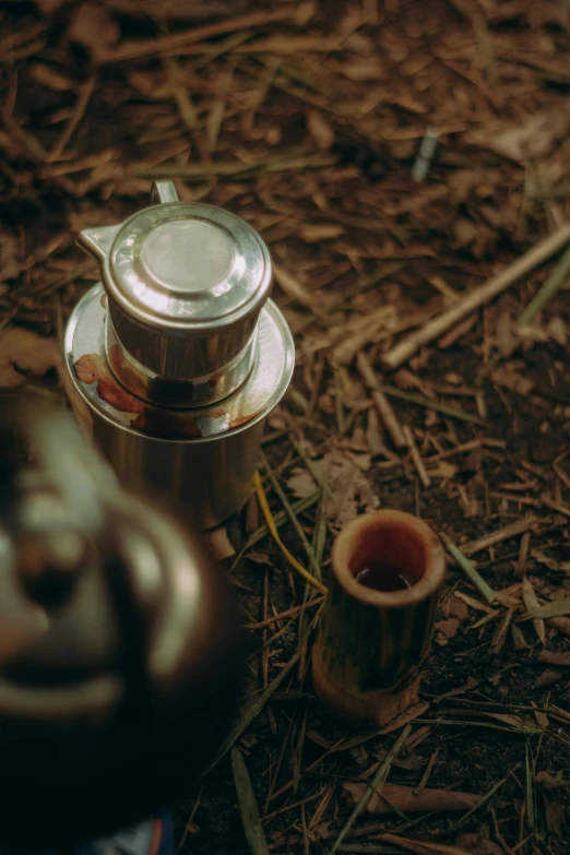 a coffee pot sitting on the ground next to a cup, ritual in a forest, vietnam, teaser, small