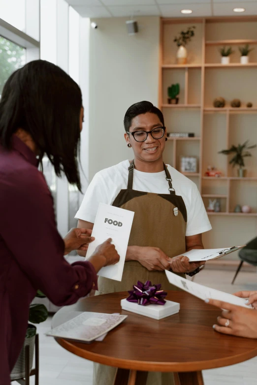 a group of people standing around a table, at checkout, white apron, holding notebook, trending photo