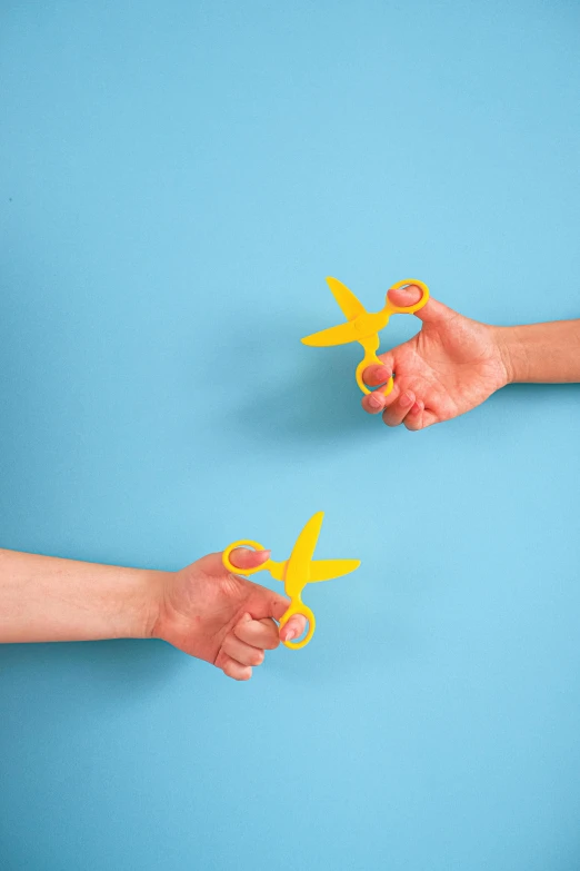 a pair of hands holding a pair of scissors, pexels, conceptual art, yellow and blue and cyan, toys, diecut, duel