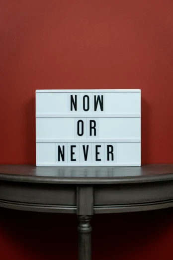 a sign that says now or never on a table, inspired by Reinier Nooms, unsplash, light box, neosvr!!!, no - text no - logo, n 2