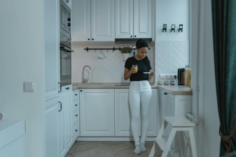 a woman standing in a kitchen looking at her cell phone, pexels contest winner, white pants, full body 8k, gif, black young woman