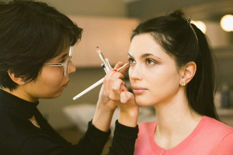 a woman putting makeup on another woman's face, trending on pexels, hyperrealism, long crooked nose, colourised, person in foreground, lane brown