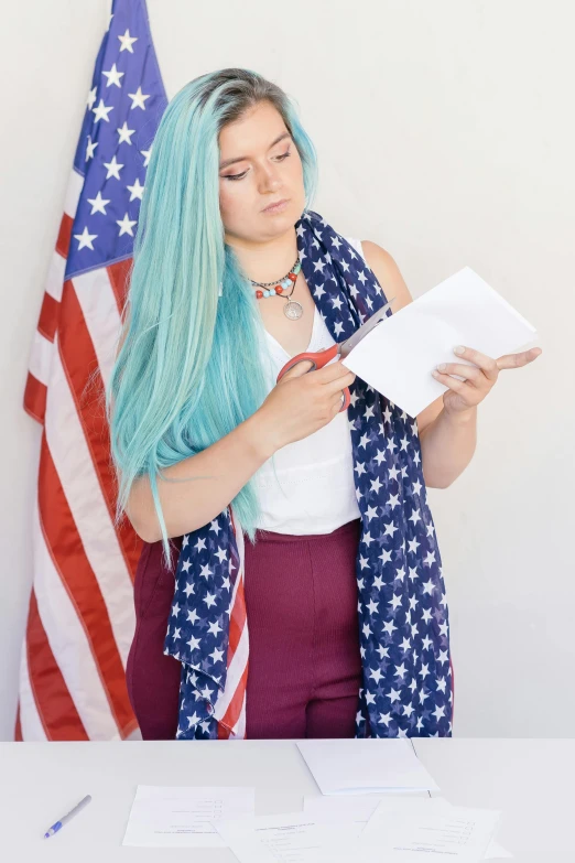 a woman with blue hair standing in front of an american flag, trying to read, teal hair, with white long hair, in front of white back drop