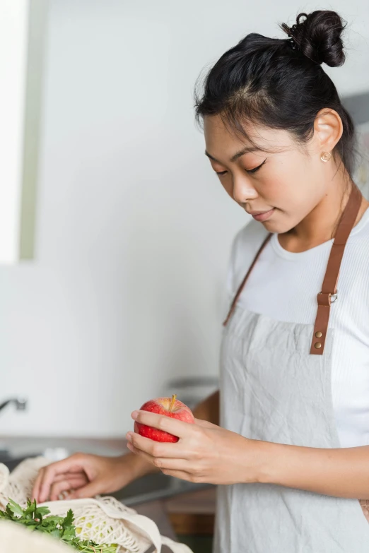 a woman standing in a kitchen preparing food, inspired by Li Di, pexels contest winner, red apple, wearing a light shirt, profile image, asian male