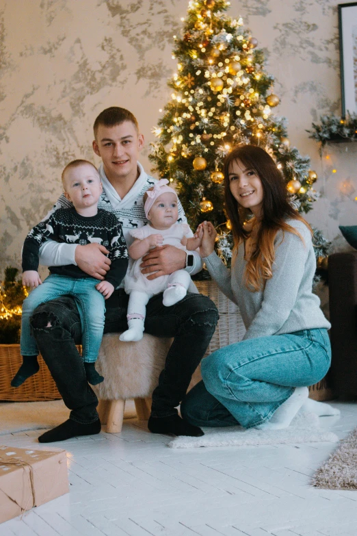 a family posing for a picture in front of a christmas tree, a picture, by Julia Pishtar, pexels, realism, ukraine. professional photo, sitting on the floor, 15081959 21121991 01012000 4k, video footage