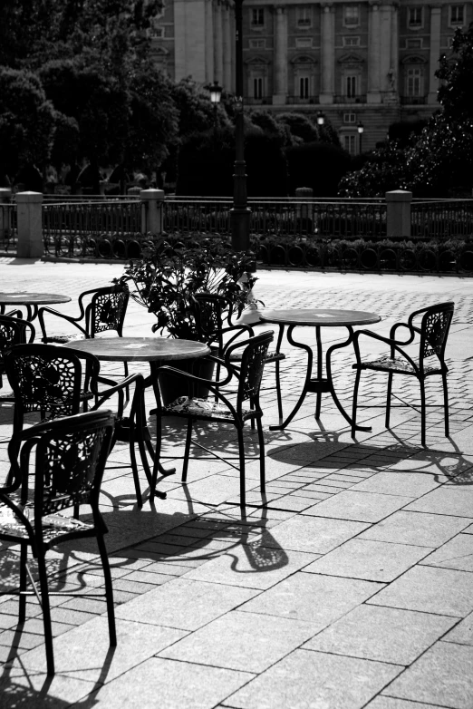 a black and white photo of a table and chairs, city square, unhappy, afternoon sun, taken in the late 2000s