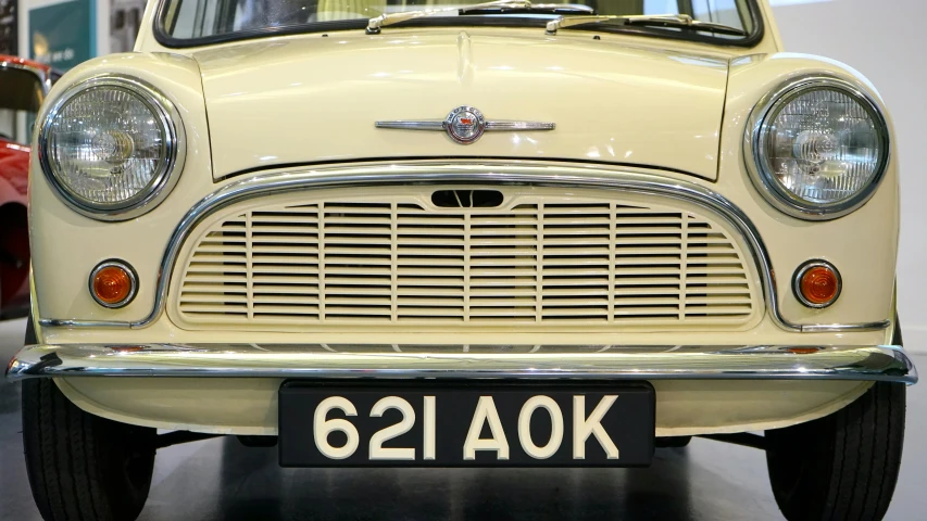 an old car is on display in a museum, an album cover, by Kev Walker, unsplash, mini cooper, cream and white color scheme, pretty aquiline nose, extremely polished