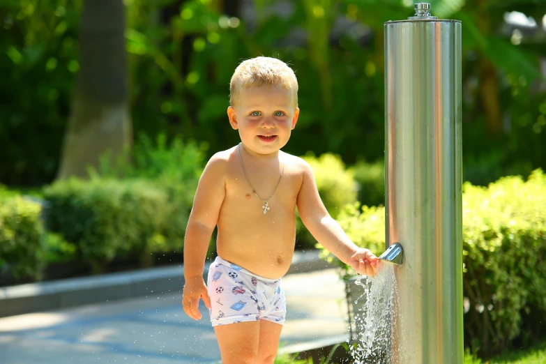 a little boy standing next to a water fountain, sparky swimsuit, bellybutton, thumbnail, lifestyle